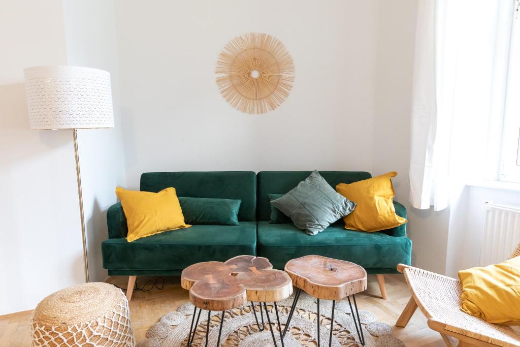 uma sala de estar com um sofá verde e duas mesas em Arbio Apartments near Mariahilferstraße em Viena