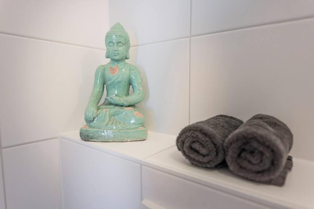 a green statue sitting next to towels on a shelf at De Kaasmakerij - Ruim vakantiehuisje op Huize Blokland in Hem