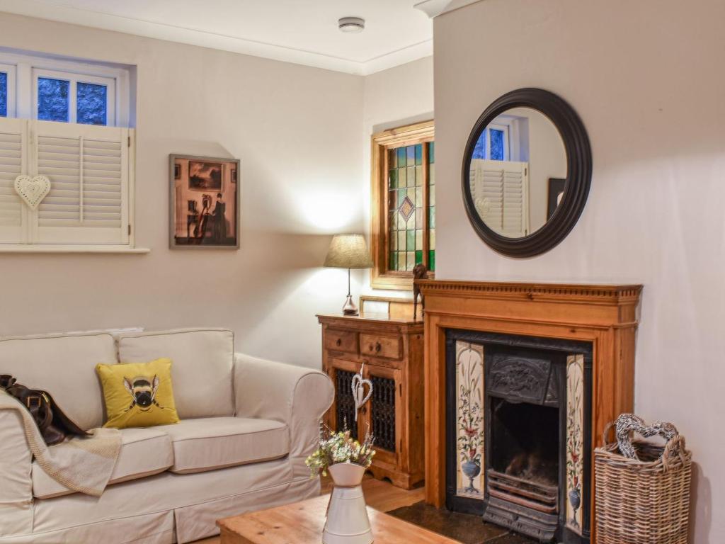 a living room with a couch and a mirror at Cobblers Cottage in Petworth