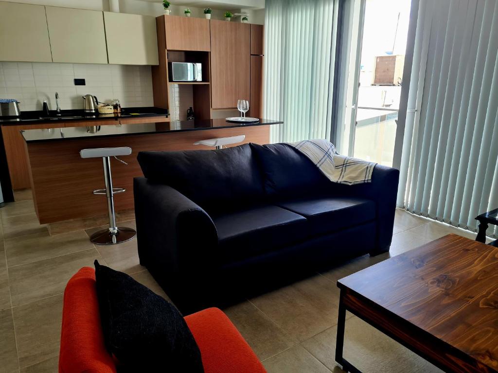 ein Wohnzimmer mit einem schwarzen Sofa und einer Küche in der Unterkunft Mendoza Chill in Mendoza