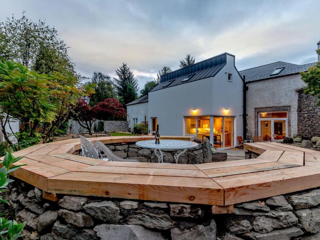 un patio con una mesa y una pared de piedra en Stable Cottage - Uk34898, en Dunira