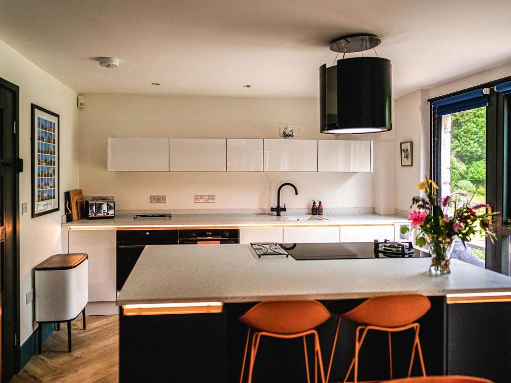 a kitchen with a large island with orange bar stools at Moorlands in Chilcompton
