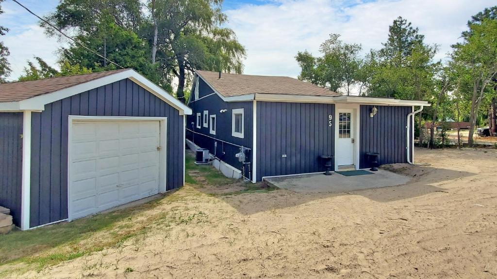 a blue house with a garage in a yard at Main Beach River Retreat - Wasaga Beach 1 - Main Strip - 95 Mosley St in Wasaga Beach