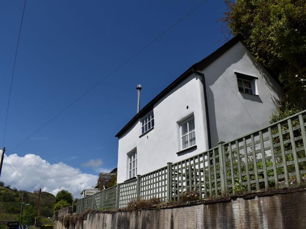 a white house with a fence in front of it at Strawberry Cottage in Combe Martin