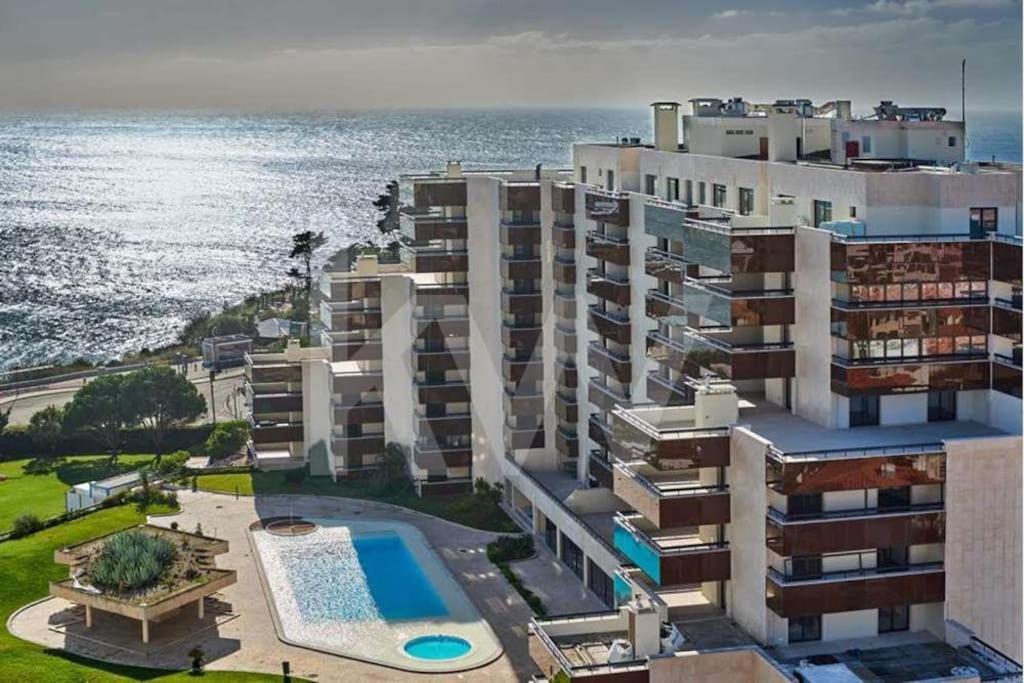 an apartment building with a swimming pool and the ocean at Health Village Apartments in Cascais
