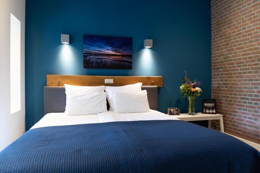 a blue bedroom with a large bed with white pillows at Beerze Brouwerij Hotel in Vessem