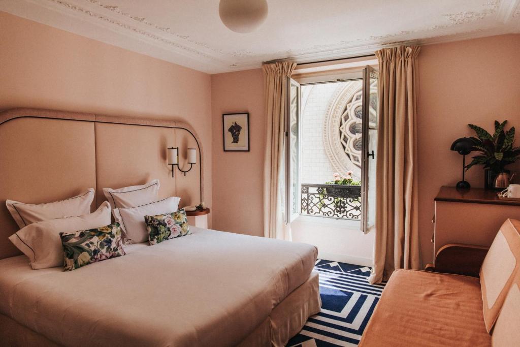 sypialnia z dużym łóżkiem i oknem w obiekcie Hôtel Bienvenue w Paryżu