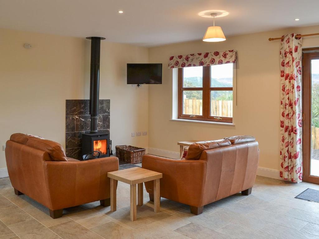 a living room with two chairs and a fireplace at Quails Nest in Edlingham