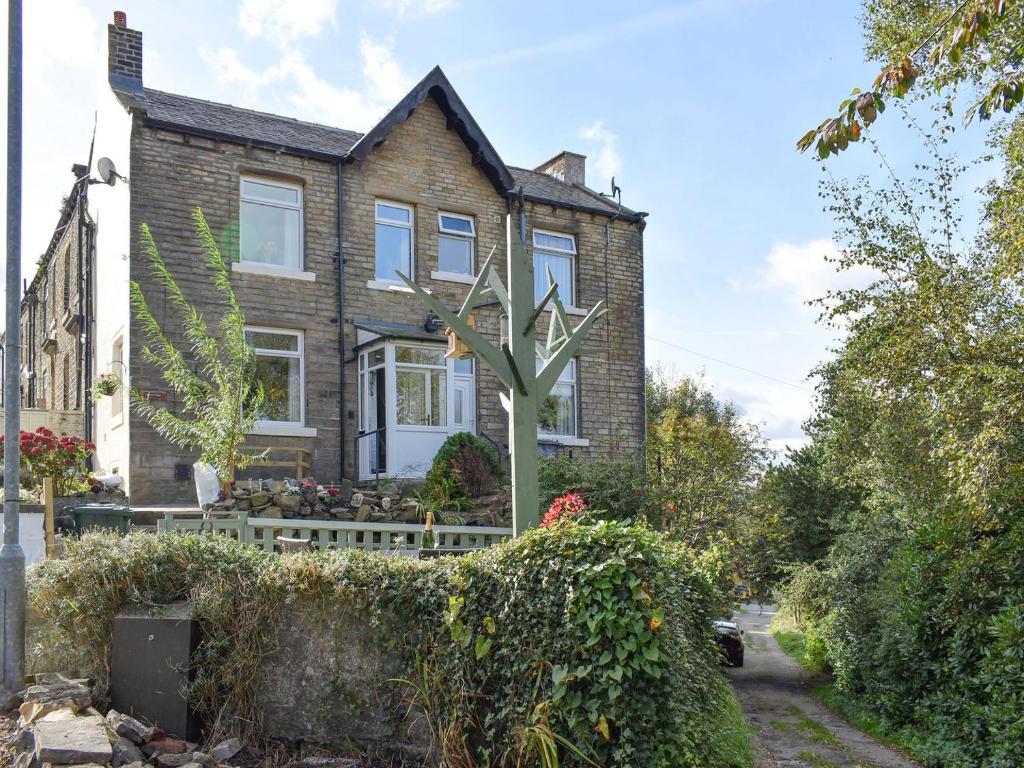 a brick house with a tree in the front yard at Slant End Cottage in Golcar