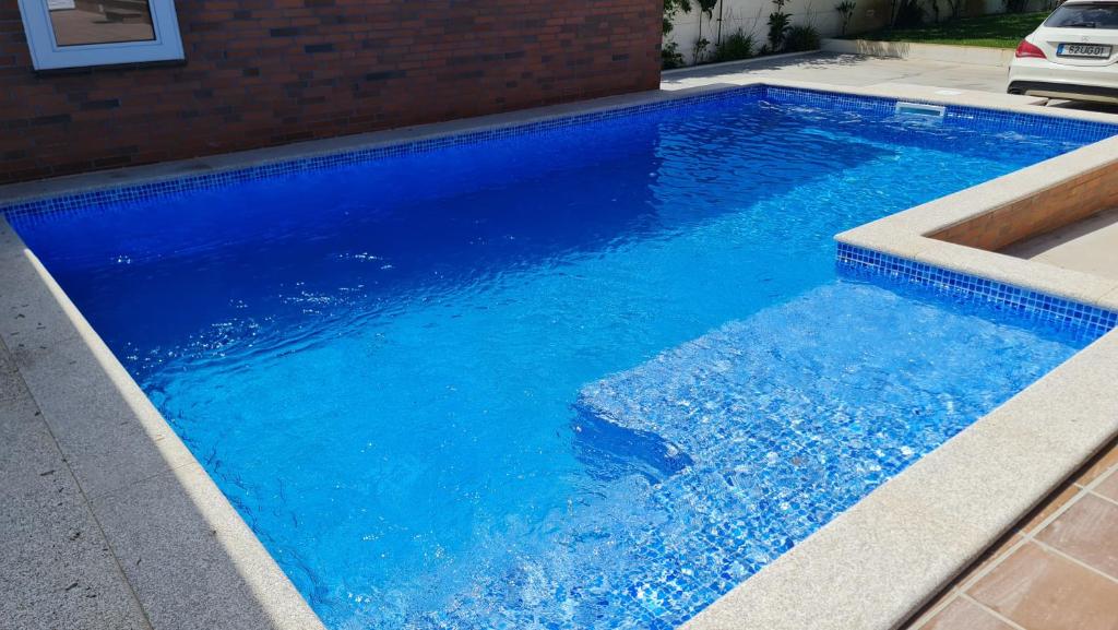 a swimming pool with blue water in a house at Pinheiro Manso in Apúlia