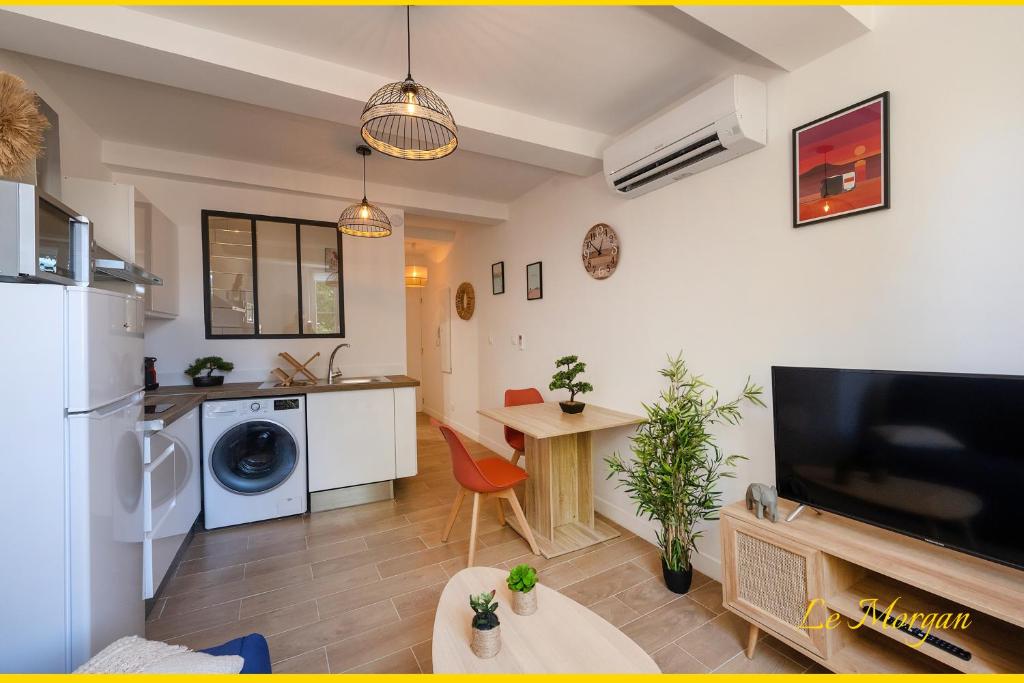 una cucina e un soggiorno con grande TV e tavolo di Le Morgan - Magnifique appartement cours principal plein centre avec parking a Salon-de-Provence