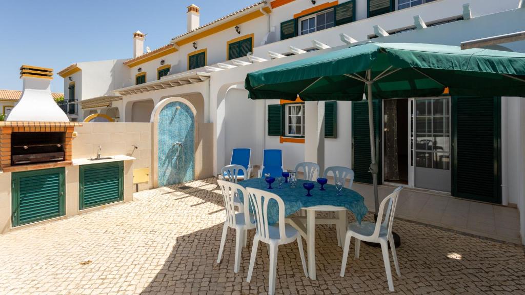 a table with chairs and a green umbrella on a patio at Wonderful Algarvinian Home by LovelyStay in Vila Nova de Cacela