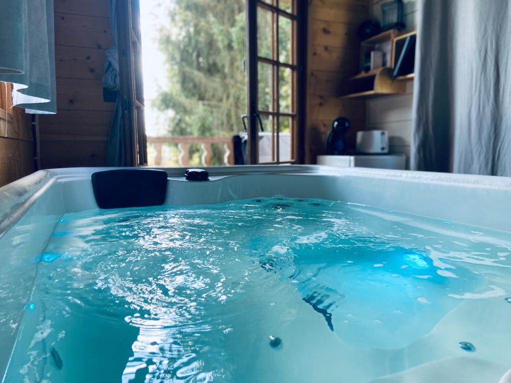 a tub filled with blue water in a bathroom at Chambre avec spa privé in Candor