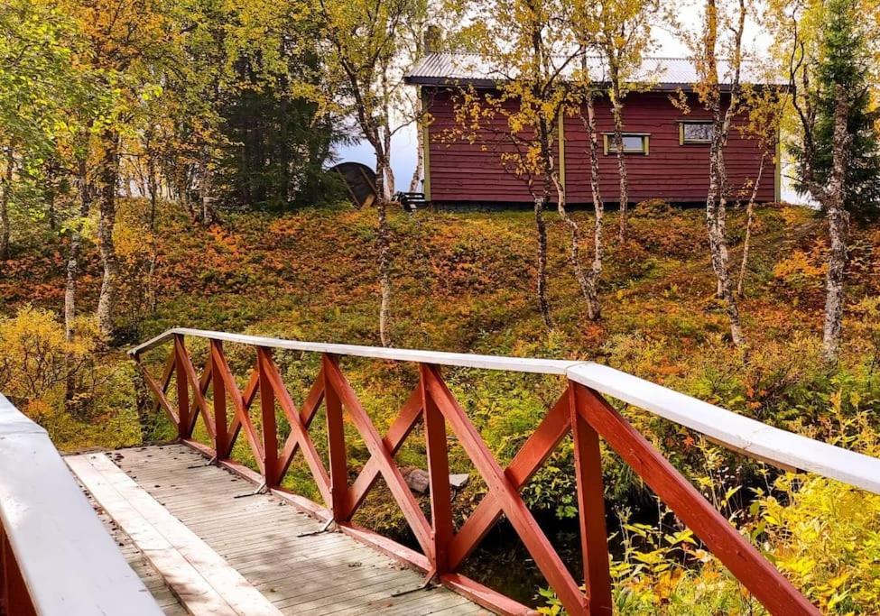 a bridge over a river with a house in the background at Cosy cabin in North-Norway, Nearby Senja. in Sorreisa