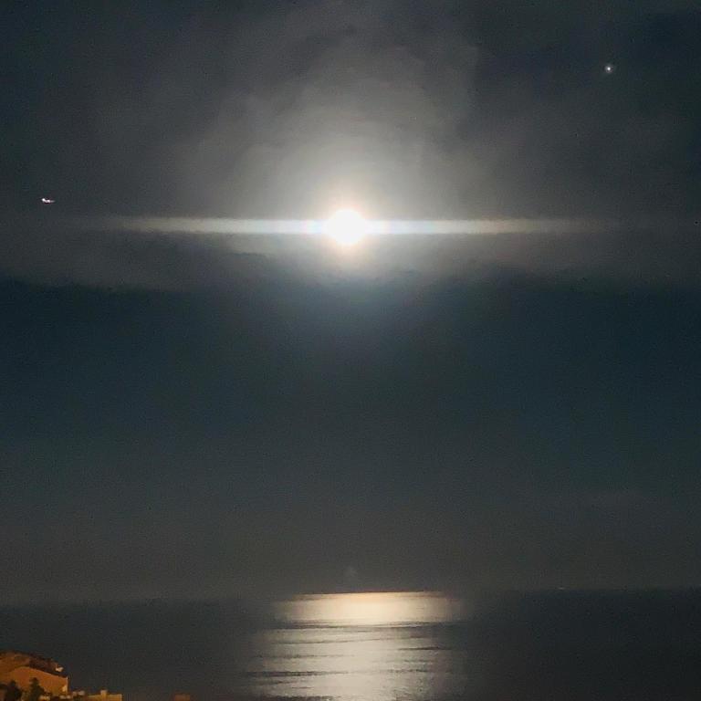 a full moon rising over the ocean at night at SARA RIVIERA Costa Plana in Cap d'Ail