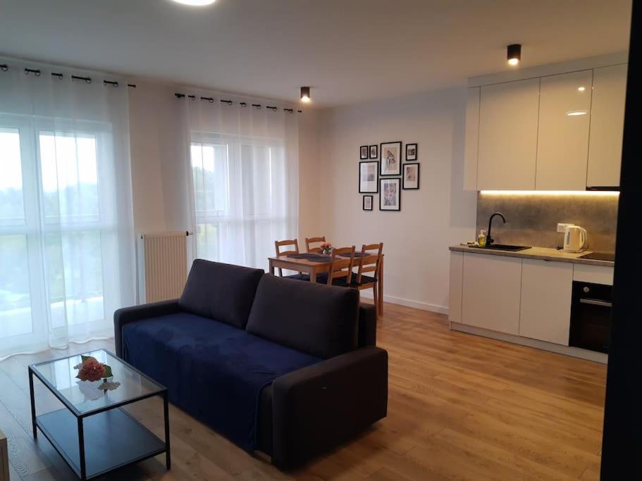 sala de estar con sofá azul y cocina en NEW APARTMENT Wołyńska - przestronny, z widokiem, czysto, parking, balkon, en Rzeszów