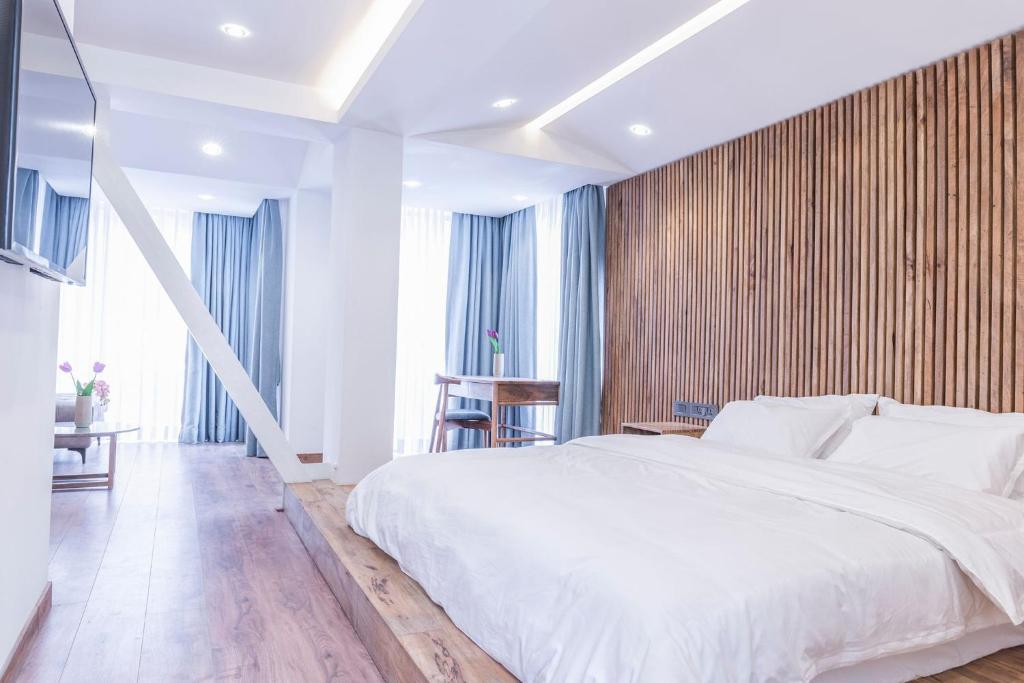 9ine Thamel Hotel في كاتماندو: غرفة نوم بسرير ابيض وجدار خشبي
