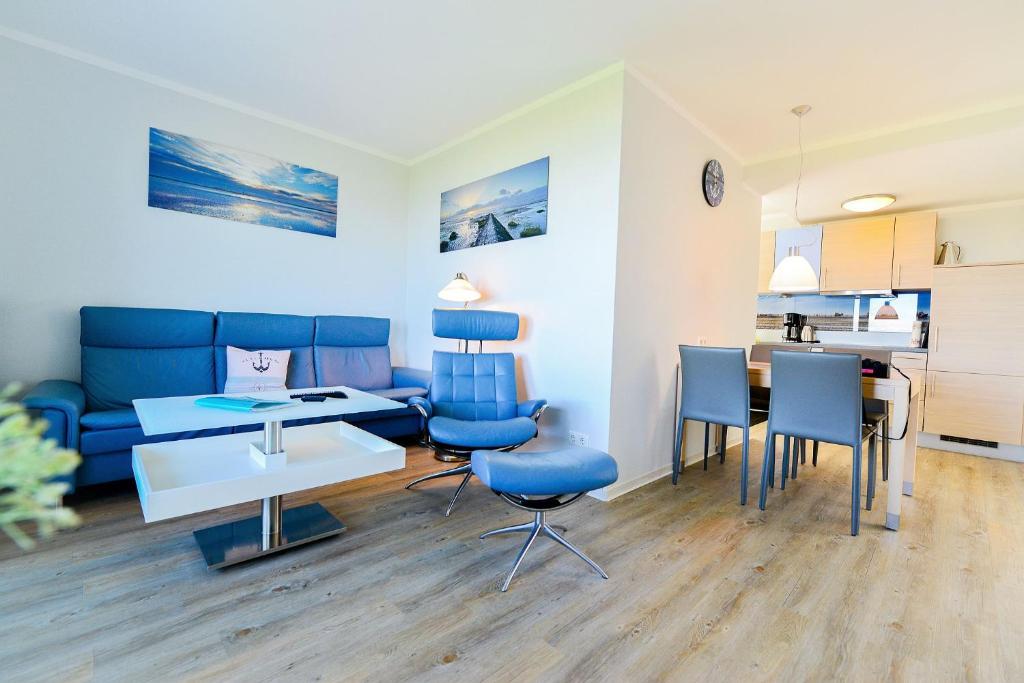 uma sala de estar com um sofá, uma mesa e cadeiras em Beach Lodge BL03 em Cuxhaven