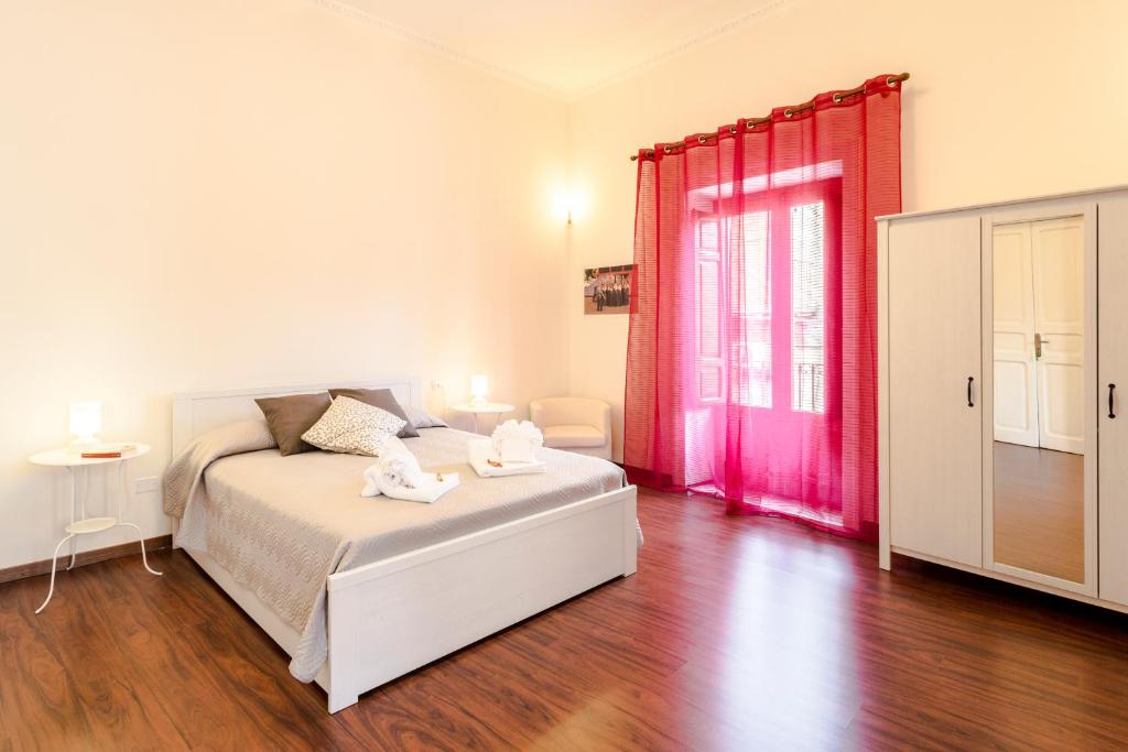 a bedroom with a white bed and red curtains at Case Spazioscena - Calliope in Castelbuono