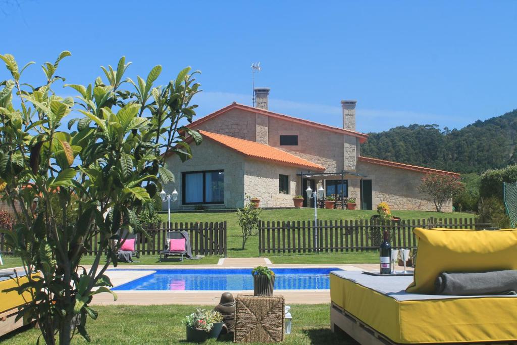 a villa with a swimming pool in front of a house at Luxury Singular Villa Carolina in Corrubedo