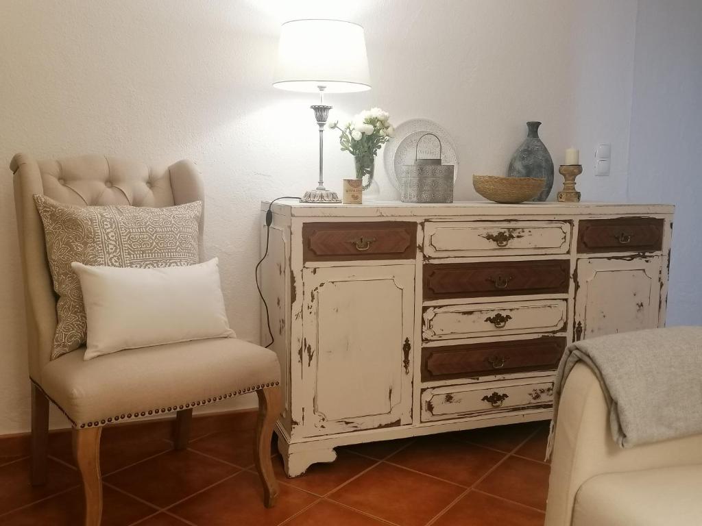 a dresser with a lamp and a chair with a pillow at A Casa Pequenina - Escusa, Marvão in Marvão