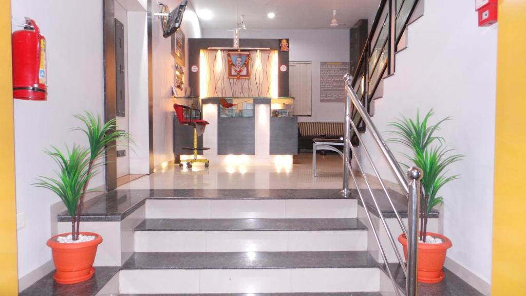 a lobby with a staircase with potted plants at Hotel Royal Residency Executive in Miraj