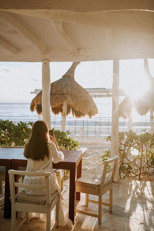 a woman sitting at a table near the beach at Coco Unlimited in Tulum