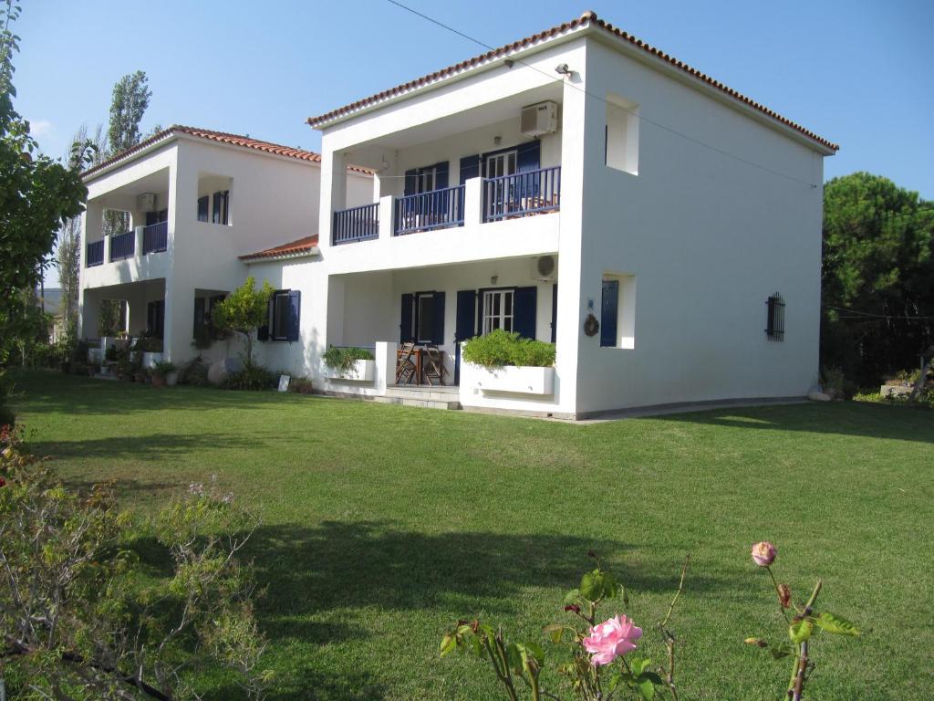 een groot wit huis met een grote tuin bij Eressos Ilios Apartments in Skala Eresou