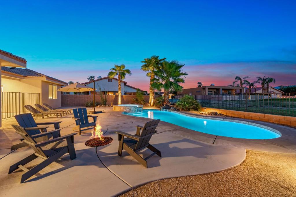 a backyard with a swimming pool with chairs and a fire pit at Palms Place in Indio in Indio