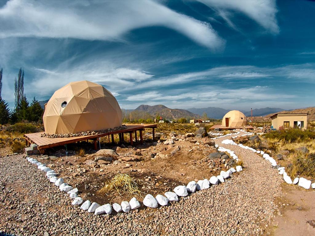 une yourte avec une table et des rochers sur un champ dans l'établissement Vista Pedra Glamping, à Potrerillos