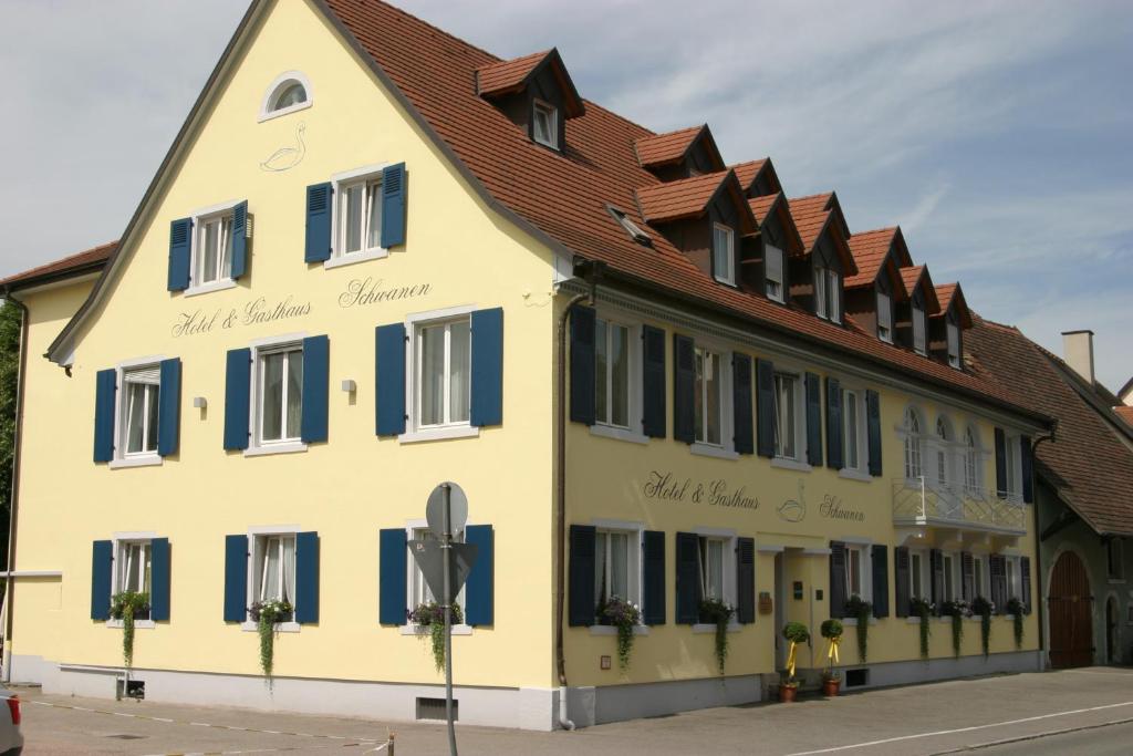 ヴァイル・アム・ラインにあるHotel-Restaurant Schwanenの青窓・茶屋根の黄色い建物