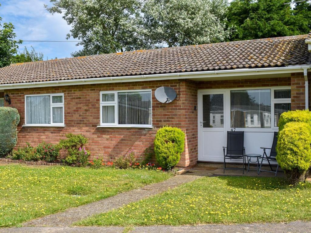 a brick house with a white door and two chairs at Willow Cottage in Kessingland