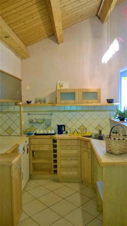a large kitchen with wooden cabinets and tile floors at CHAMBRES D&#39;HOTES 2 à 4p ou GITE DE GROUPE 15p, 7 ch, 6 sdb, parc et salle de réception in Villeneuve-de-Berg