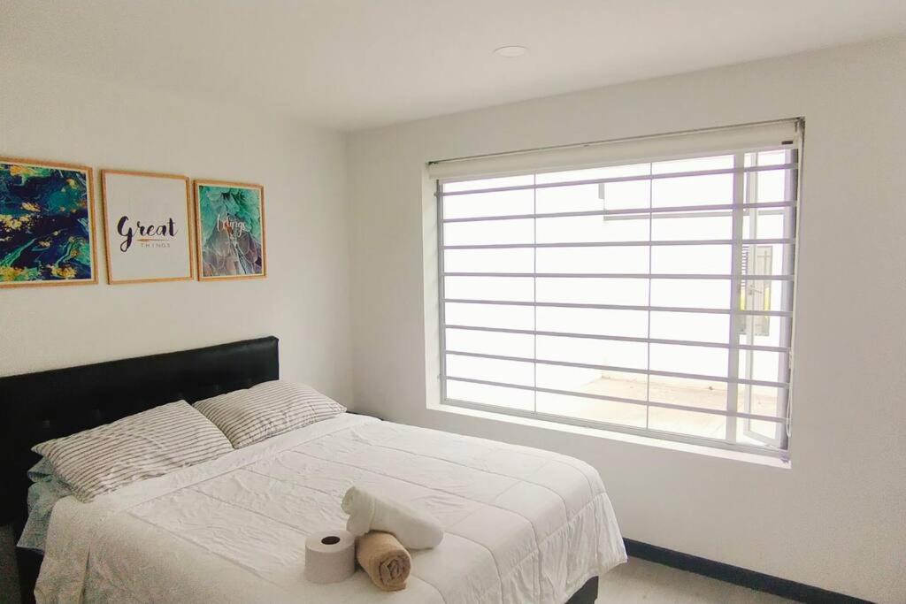 1 dormitorio con 1 cama con sombrero y ventana en 4 Apartaestudio Cedritos completo, en Bogotá