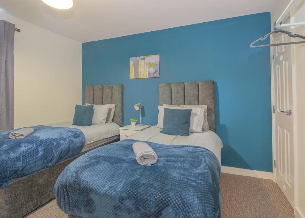 1 dormitorio con 2 camas y paredes azules en Ground Floor Apartment Private Parking Sleeps 5 near City Centre and Shopping Centre en Birmingham