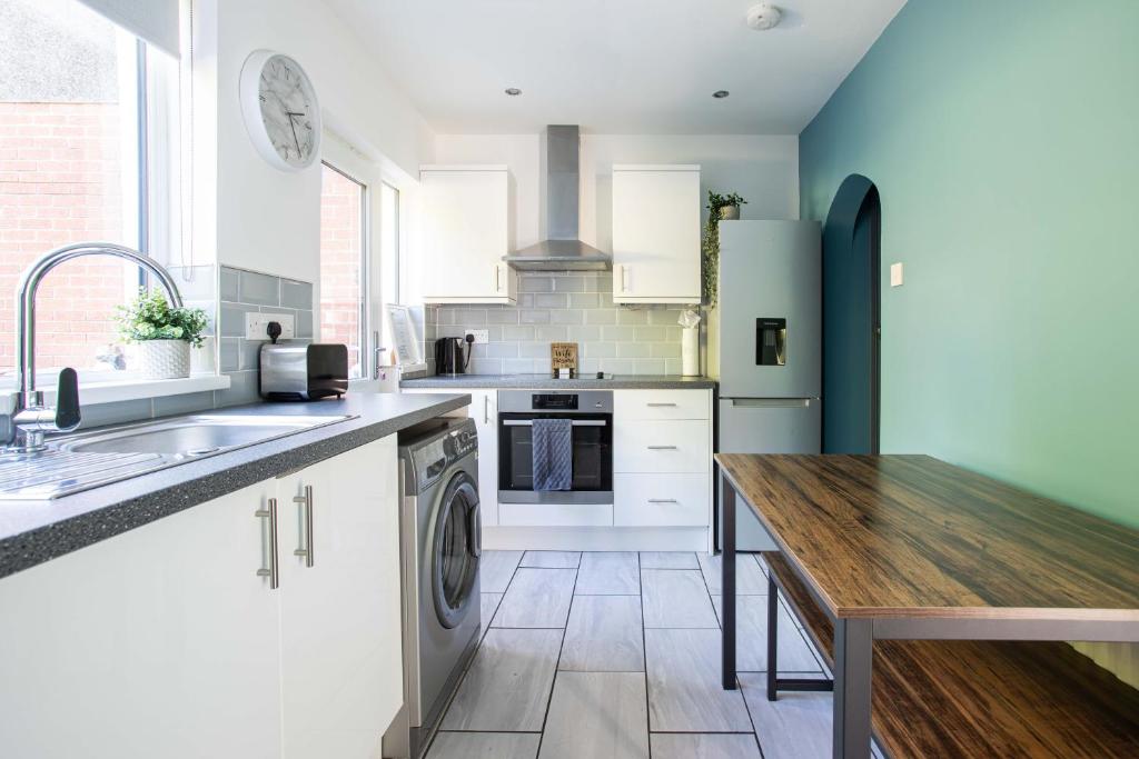 a kitchen with white cabinets and a wooden table at Fully Refurbished North Belfast Home in Belfast