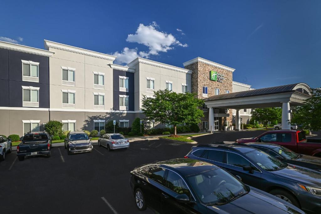 un estacionamiento con autos estacionados frente a un edificio en Holiday Inn Express Charlotte Southeast - Matthews, an IHG Hotel, en Charlotte