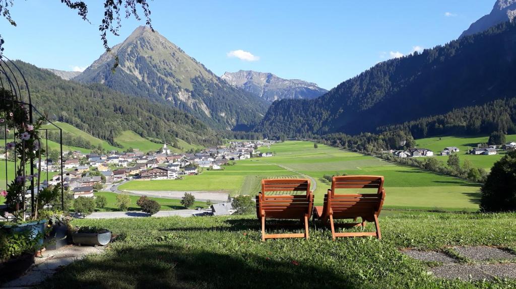 three chairs sitting on a hill overlooking a valley at Fernblick Frühstückspension in Schoppernau