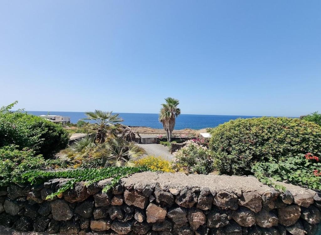una pared de piedra con el océano en el fondo en Perla Nera I DAMMUSI DI SCAURI en Pantelleria