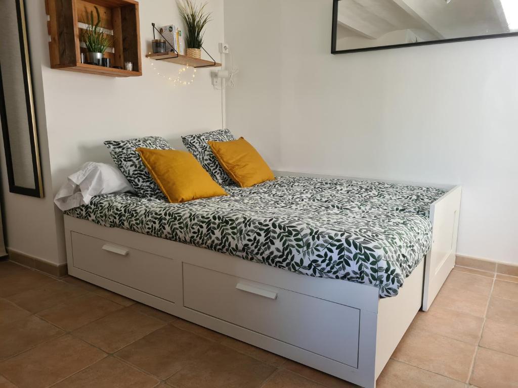 uma cama com almofadas amarelas num quarto em Studio vallon d'Azur à Carqueiranne em Carqueiranne