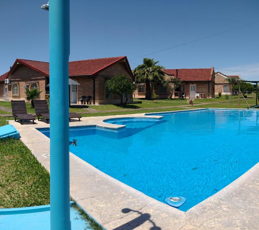 a large blue swimming pool in front of a house at Hotel de Campo con Piscina y Cabañas- Ideal Relax en Concordia in Concordia