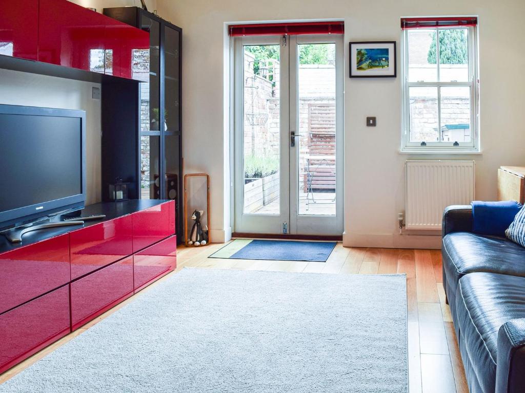 a living room with a tv and red cabinets at The Pad in Lillington