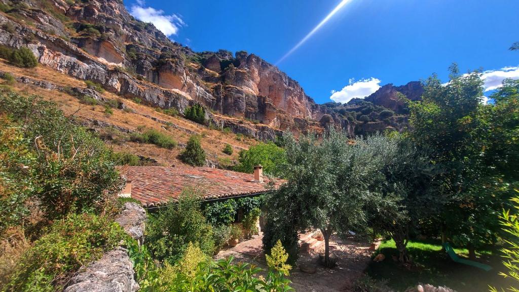 un arco iris sobre una montaña con una casa y árboles en Casa Corazón de piedra en el Río Dulce en Aragosa