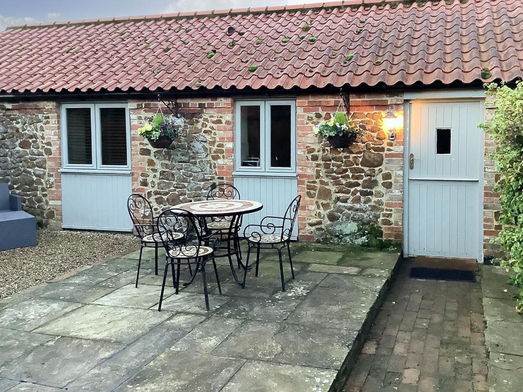 a patio with a table and chairs in front of a building at Bramble Cottage in Ingoldisthorpe