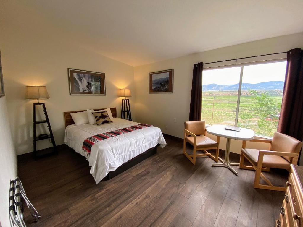 Schlafzimmer mit einem Bett, einem Tisch und einem Fenster in der Unterkunft The Riverside Ranch Motel and RV Park Southern Utah in Hatch