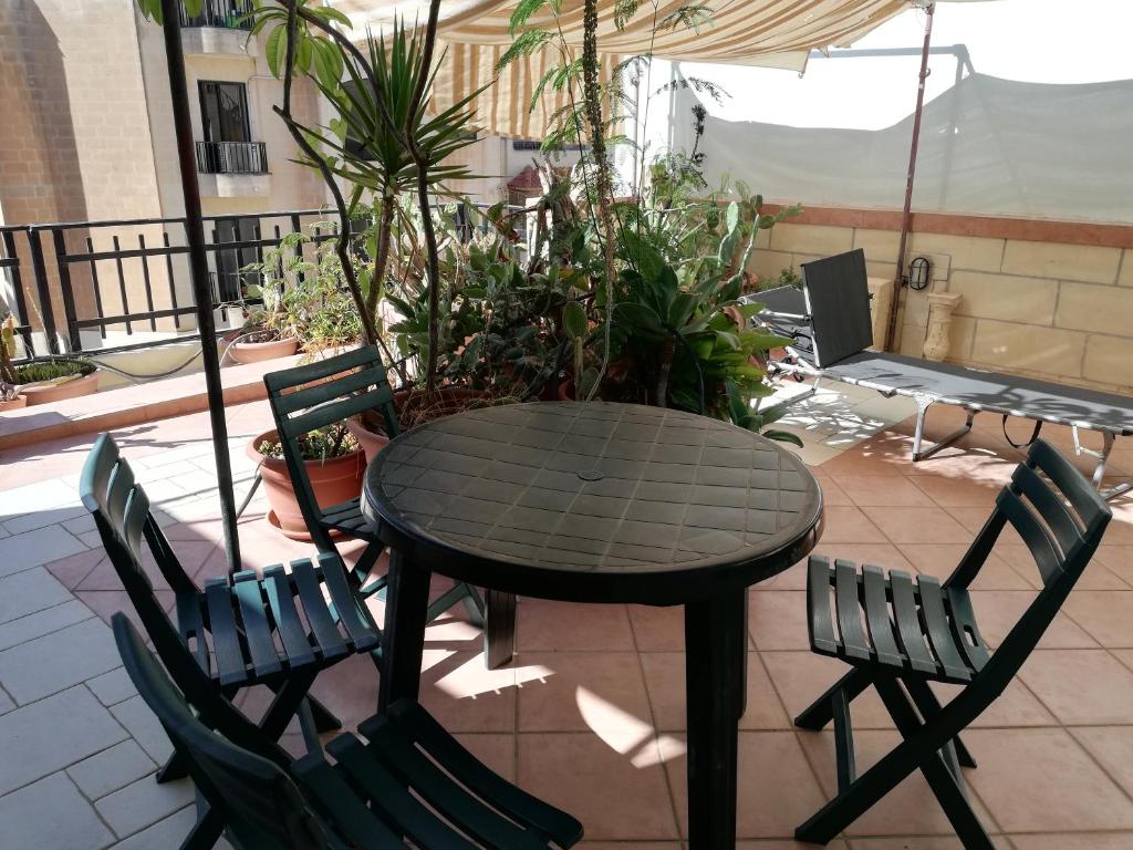 una mesa y sillas en un patio con plantas en The roof garden, en Marsaskala