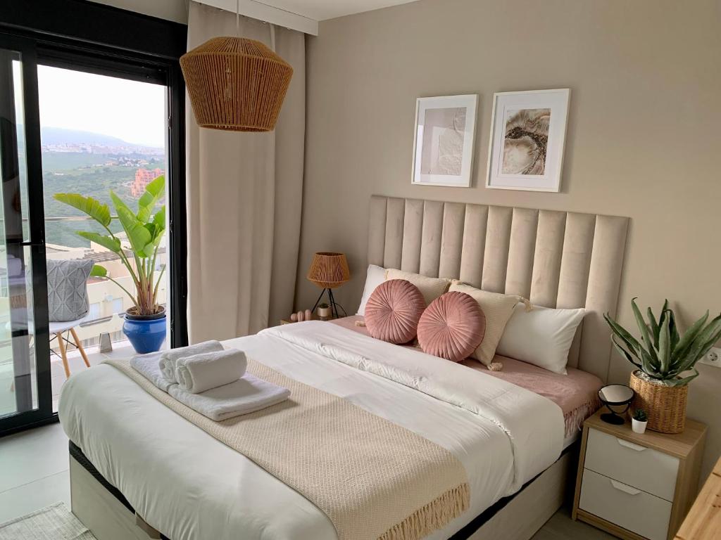 a bedroom with a large bed with pink and white pillows at Blue Sunset Luxury Seaview Apartment La Duquesa in Manilva