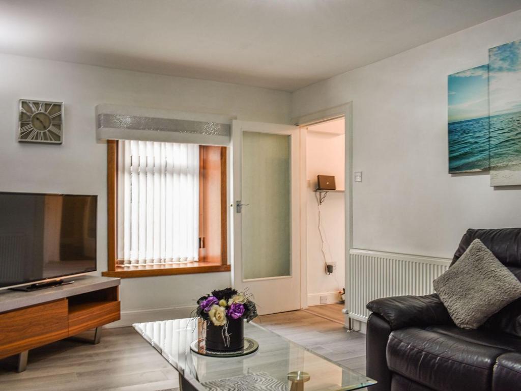 a living room with a couch and a tv at Belger Cottage in Inverallochy