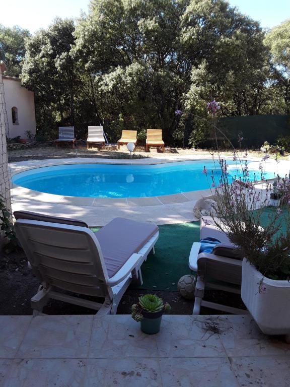 une piscine avec deux chaises longues à côté dans l'établissement MAISON FAMILIALE, à Montaren-et-Saint-Médiers