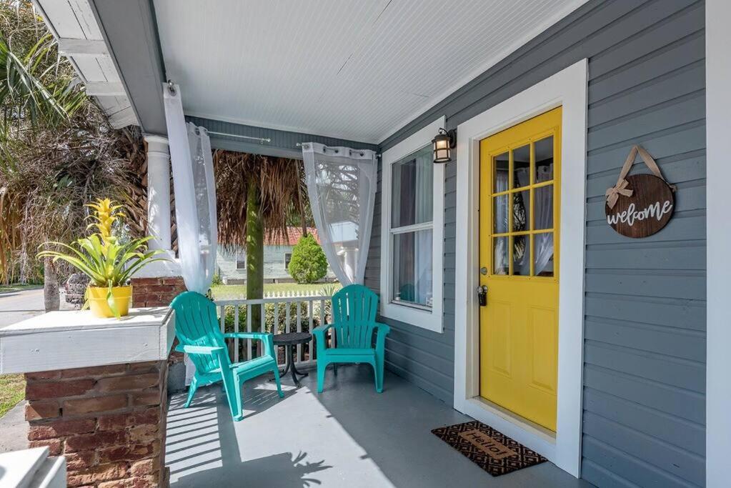 a porch with two chairs and a yellow door at Gambino Getaway Shotgun style apt in the heart of Ybor City in Tampa
